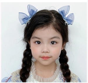 Detailed view of blue mesh bow hair clips worn on a little girl's braided hair