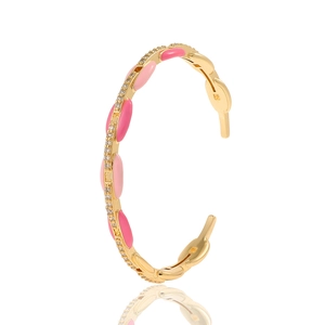 Close-up of golden open bangle with pink enamel ovals and micro-pave white zircons