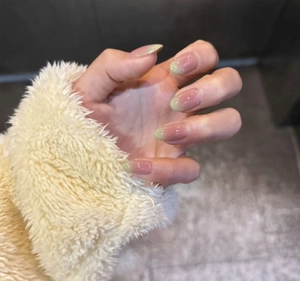 Detail of almond-shaped pink and green gradient press-on nails with glossy finish