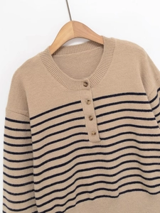Detail of striped knit sweater with round neck and tortoiseshell-style buttons