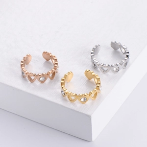 Detailed view of three open heart-shaped rings in rose gold, gold and silver with cubic zirconia