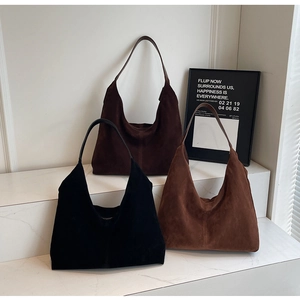 Three premium hobo bags in black, dark brown, and caramel suede displayed on stone steps