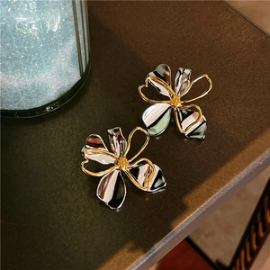 Close-up of contrast flower earrings with hollow gold edges and enamel petals