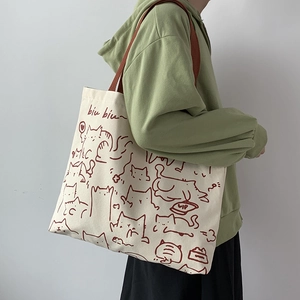 Close-up of canvas tote bag showing hand-drawn cat illustrations and brown strap detail