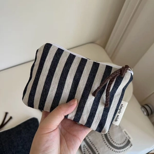 Detailed macro view of black and white striped canvas pouch with woven zipper puller