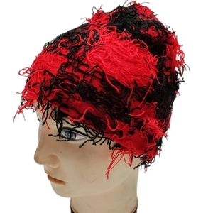 Detail of red and black distressed knit hat showing fuzzy fringe texture and punk style