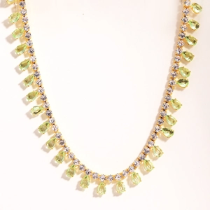 Detail of gold plated necklace featuring light green teardrop gems and zircon tassels