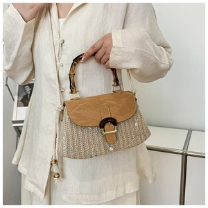 Close-up of a woven straw bag featuring floral embroidery and a vintage bamboo handle