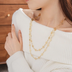 Detail shot of a double-layered gold necklace with diamond-shaped hollow clover pendants