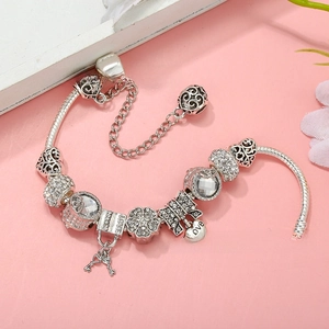 Detailed close-up of silver snake chain bracelet with heart charms and a key pendant