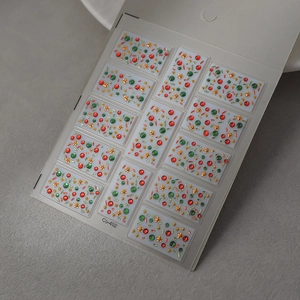 Macro view of Christmas nail art stickers with red and green rhinestones and gold stars