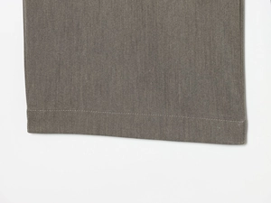 Gros plan du pantalon en sergé gris-brun montrant les détails de couture de l'ourlet