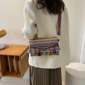 Detailed shot of bohemian woven crossbody bag with colorful tassels and jacquard strap