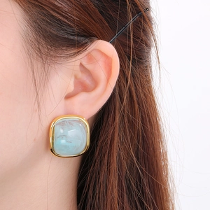 Détail montrant la boucle d'oreille carrée en résine marbrée bleu clair sur le mannequin