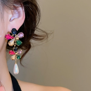 Detailed view of luxury flower stud earrings with vibrant crystals and a drop pearl