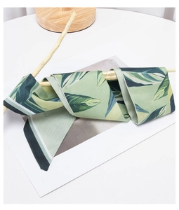 Detail of botanical green leaf print silk scarf with smooth texture on a branch
