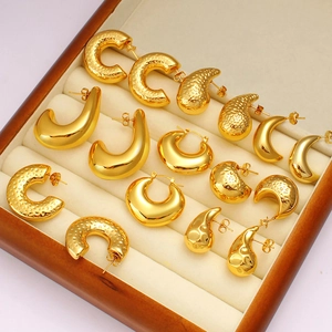 Close-up of assorted gold stud earrings in geometric shapes displayed in a jewelry box