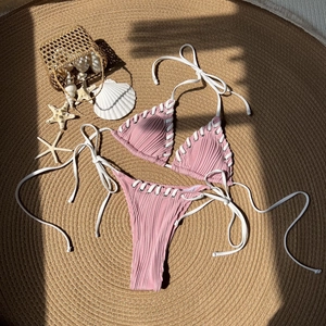 Pink ribbed bikini set with adjustable side-tie bottoms and seashell beach background