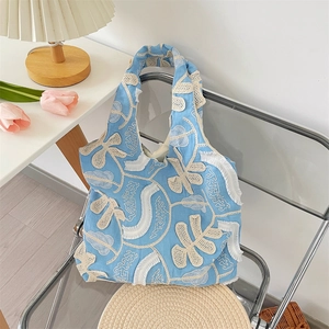 Détail du sac cabas bleu clair avec broderies de papillons en dentelle blanche et fleurs