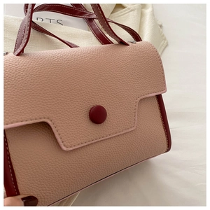 Detail shot of pink lychee texture leather with contrast stitching and red buckle decor