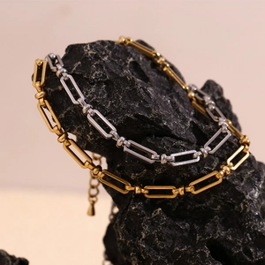 Minimalist 14K gold and silver plated paperclip chain anklet on black rock surface