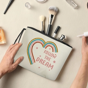 Rainbow heart canvas makeup bag with Follow the Dream text on a bright desk setting