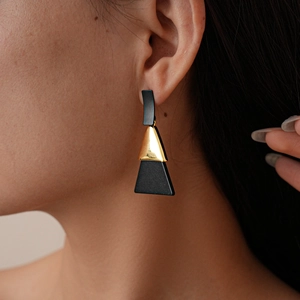 Boucles d'oreilles géométriques triangles noir mat et or portées par un mannequin