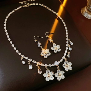 Detailed view of zircon flower necklace and teardrop earrings set in gold metal