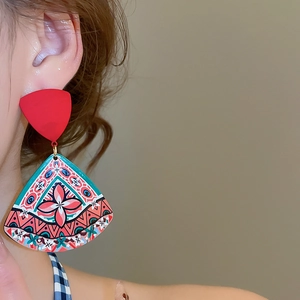 Close-up of ethnic style printed fan-shaped earrings with red triangular studs
