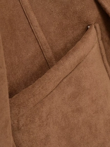 Gros plan sur la texture du daim marron et les coutures de la poche de la veste
