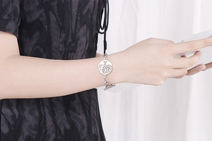Close-up of tree of life charm bracelet with toggle clasp on woman's wrist