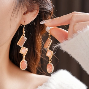 Detail of vintage gold earrings with orange gems and rhinestones worn by a model