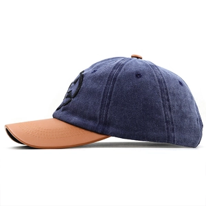 Side view of washed denim baseball cap with brown leather brim and embroidered logo