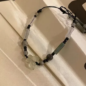 Detail of handcrafted beaded bracelet featuring a green butterfly charm and bamboo beads