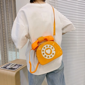 Detail of vintage rotary telephone crossbody bag in glossy yellow patent leather
