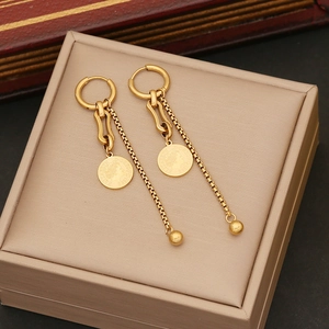 Detailed macro view of gold coin pendant earrings on a vintage leather jewelry box