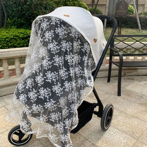 Close-up of white lace stroller cover with brown bear embroidery and mesh texture