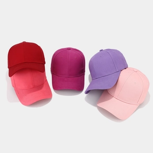 Close-up of stacked cotton baseball caps in shades of pink, purple and red
