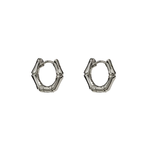 Détail de boucles d'oreilles argentées à texture bambou avec finition métal minimaliste