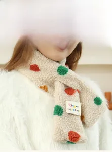 Detail of soft beige plush scarf with colorful polka dots and woven brand label