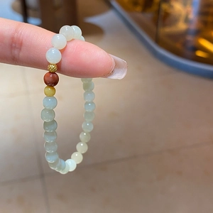 Détail d'un bracelet en perles de jade Hetian et ambre tenu dans la main