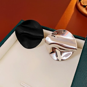 Detail of asymmetric round crinkled metal stud earrings in black and silver finishes