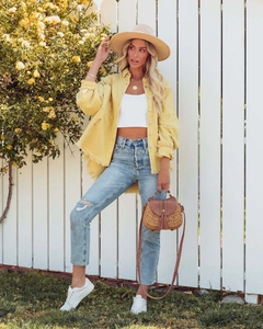 Women's yellow denim jacket with frayed fringe hem styled for a summer vacation look