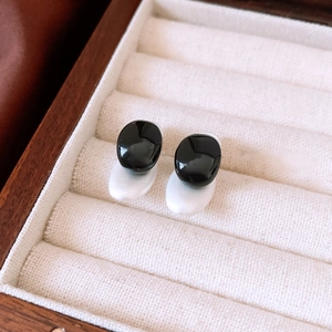 Detail of minimalist black and white oval stud earrings with smooth pebble-like texture