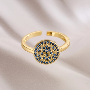 Detailed view of gold plated Hamsa hand ring with blue zircons on satin fabric