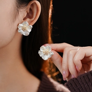 Detail of flower stud earrings featuring white pearl luster and golden bead stamens