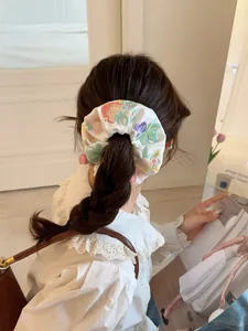 Detail of white satin scrunchie featuring delicate multi-colored floral embroidery