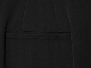 Detailed macro view of black woven fabric texture and stitching on the pocket of the suit pants