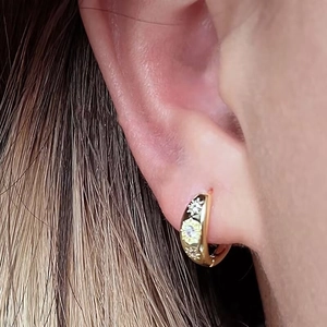 Close-up of a gold sunflower hoop earring with white petals and center zircon on an ear