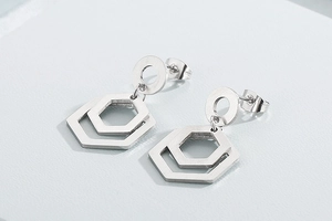 Détail macro de boucles d'oreilles hexagonales argentées avec finition métal brossé